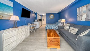 A modern living room with a grey sofa, wooden coffee table, and a TV mounted on the wall. - Stunning direct oceanfront views from your own balcony! (Daytona Beach)