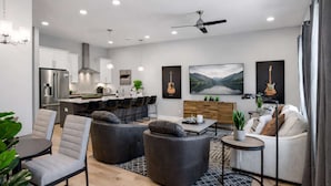 A modern living room with a sofa, ottoman, and a dining table with chairs. - Modern Rooftop Retreat • Nashville Views (Nashville)