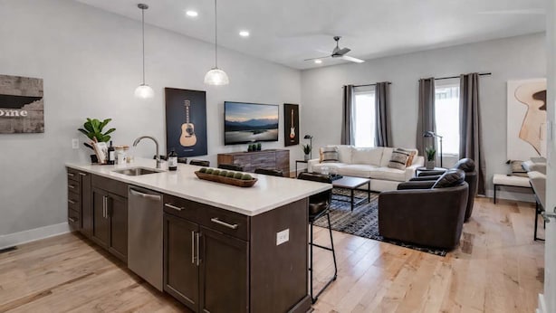 A modern kitchen with a central island, a dining area with a sofa, and a living room with a couch. - Modern Rooftop Retreat • Nashville Views (Nashville)