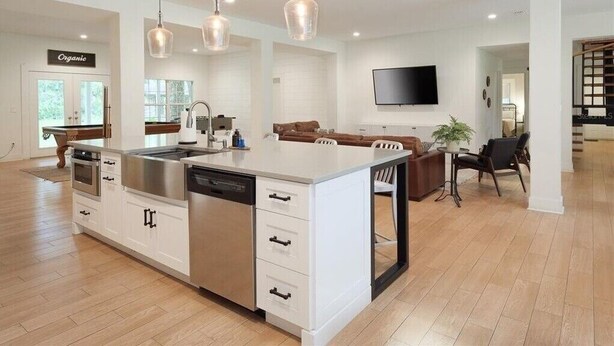 A modern kitchen with a central island, white cabinetry, stainless steel appliances, and pendant lighting.