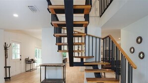 A modern staircase with wooden steps and black railings, leading to an upper floor.