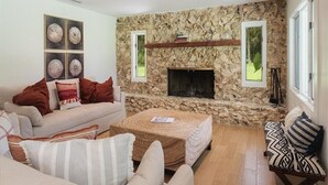 A living room with a stone wall, a fireplace, a sofa, and a coffee table.