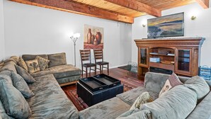 Un salon chaleureux avec un canapé d’angle, une cheminée et un tableau accroché au mur.