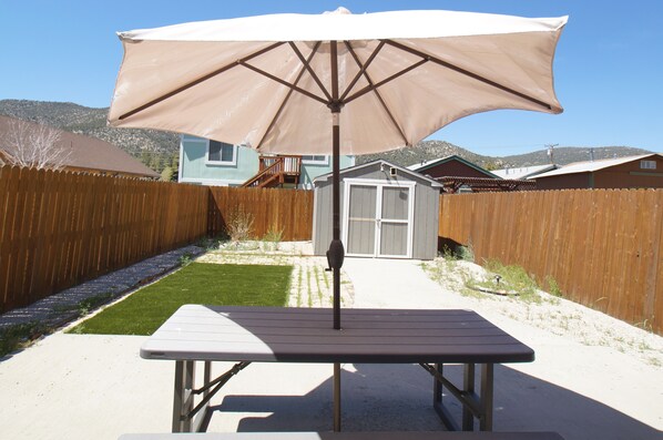 A picnic table with a canopy in a backyard. - The Rock House - Smart TV, Fireplace, Fenced Yard (Big Bear City)