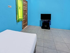 A room with a bed, a television on a stand, and a window with curtains.