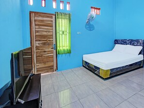 A room with a bed, a wooden door, a green curtain, and a small window with a red light.
