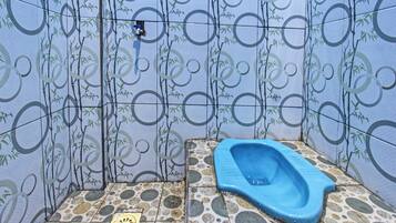 A bathroom with a blue toilet, patterned walls, and a tiled floor.