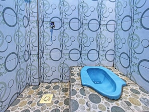 Ein Badezimmer mit einer blauen Toilette, Wandmustern und einem gefliesten Boden.