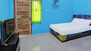 A room with a bed, a TV, a wooden door, and a window with curtains. - Spot On 91811 Rumah Inap Bunda Nurhayati (Tanak Awu)