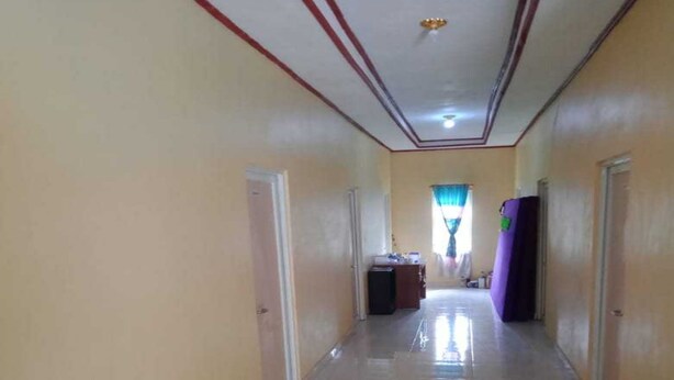 A hallway with a tiled floor, doors on both sides, and a window with curtains at the end.