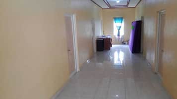 A hallway with a tiled floor, doors on both sides, and a window with curtains at the end.