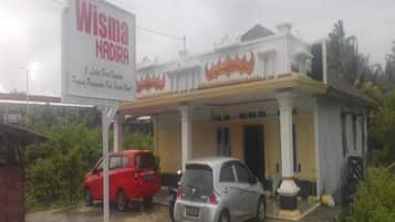 Un edificio con un letrero que dice "Wisma Nadira". Hay dos coches estacionados adelante.