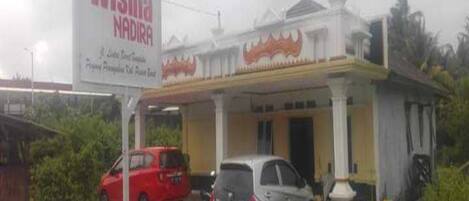A building with a sign that reads "Wisma Nadira." There are two cars parked in front.