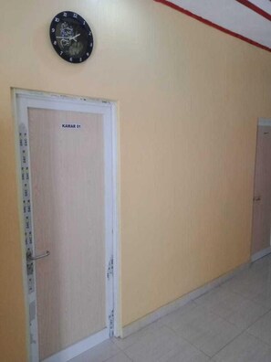 A hallway with a door labeled "KAMAR 01" and a clock on the wall. - Express O 91371 Wisma Nadira (Pesisir Utara)
