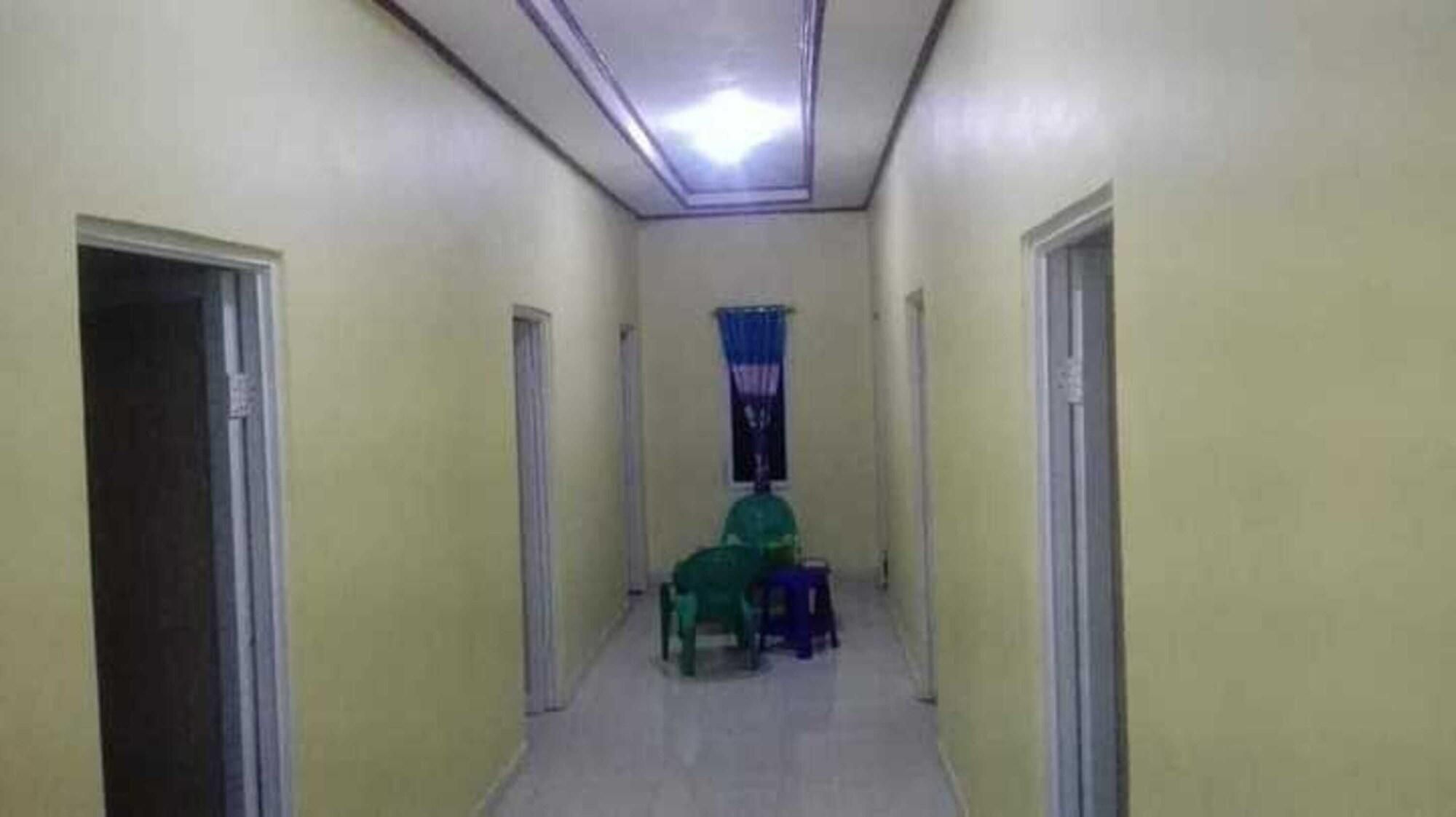 A narrow hallway with doors on both sides, a ceiling light, and a window with blue curtains.