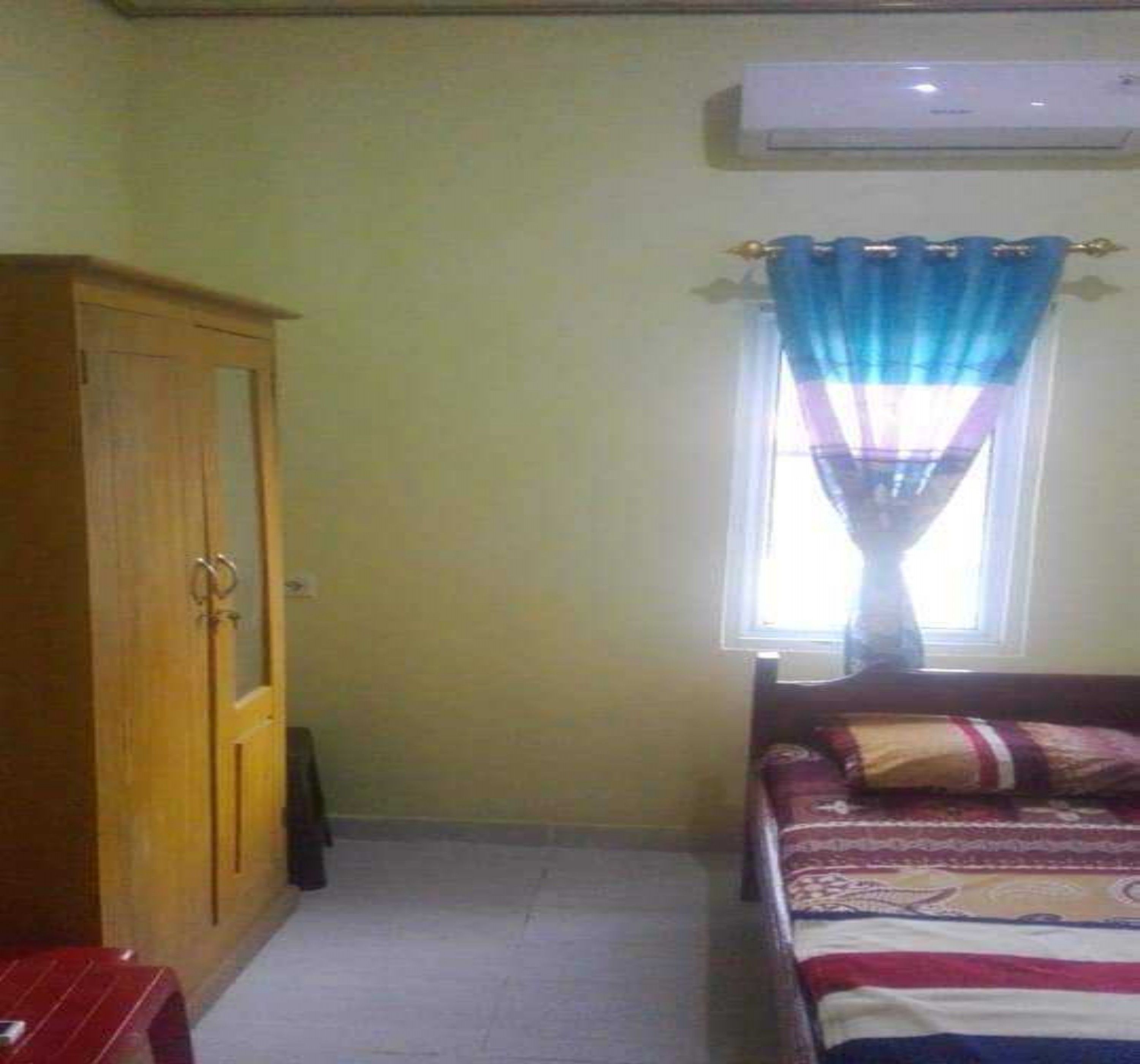 A bedroom with a bed, a wardrobe, and a window with curtains.