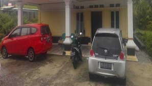 A building with a covered entrance and two parked cars.