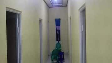 A narrow hallway with doors on both sides, a ceiling light, and a window with blue curtains.