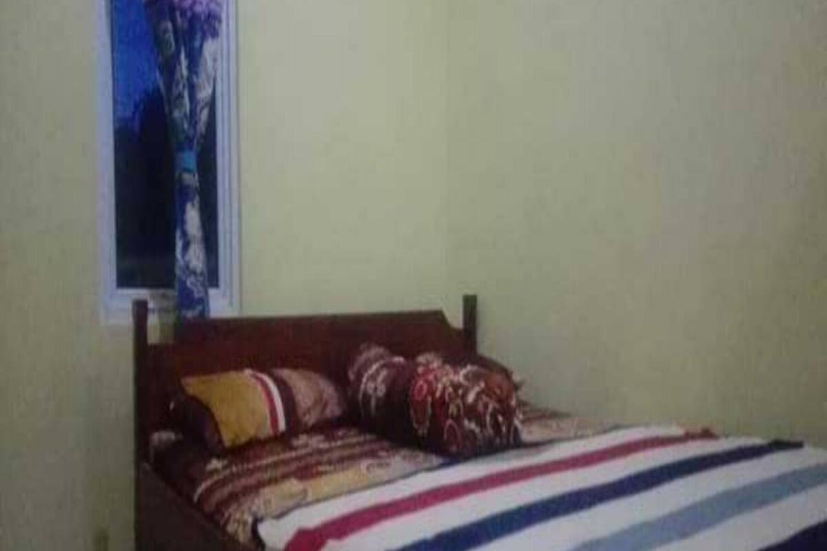 Una cama individual con una colcha a rayas, un cabecero de madera y dos almohadas.