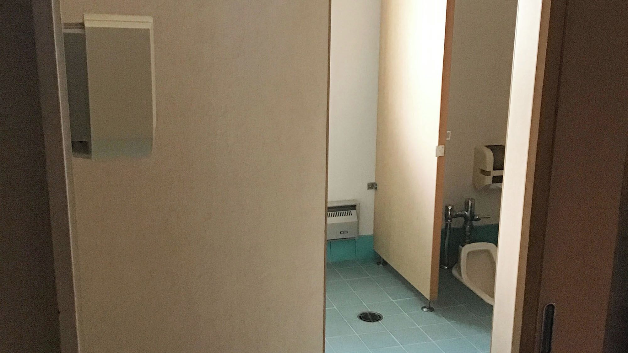 Ein schmales Badezimmer mit Toilette, Waschbecken und Lüftung.