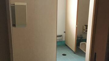 Ein schmales Badezimmer mit Toilette, Waschbecken und Lüftung.