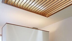 Una habitación con suelo de esteras de tatami, un bajo armazón de cama de madera, una cesta tejida y un equipo de aire acondicionado blanco.