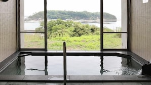 Un cuarto de spa con un ventanal grande que ofrece vistas a un lago y vegetación.