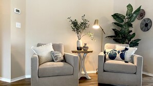Una stanza con due poltrone, un tavolino con una lampada e piante ornamentali.
