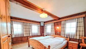 A wooden-framed bedroom with a large bed, two bedside tables, and a nightstand.