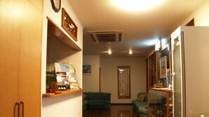 A compact living space with a wooden cabinet, a small refrigerator, a sofa, and a coffee machine. - Guesthouse Amy Monbos (Higashikagawa)