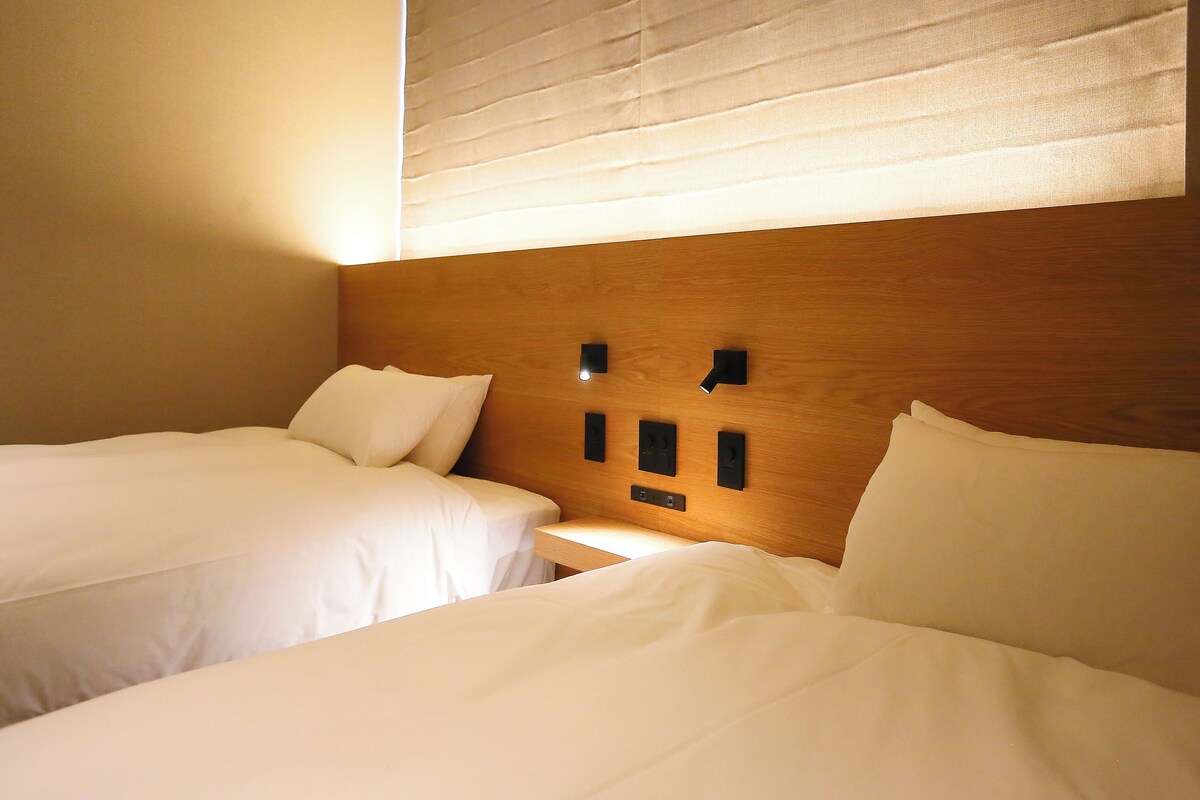 A hotel room with two beds, wooden headboard, and bedside tables.