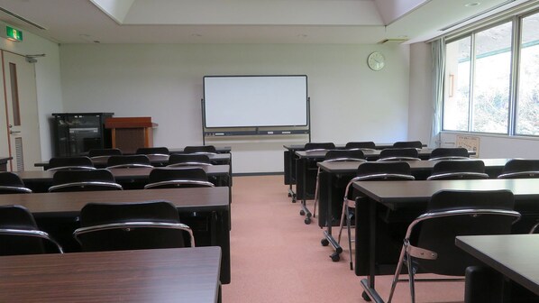 A classroom with desks, chairs, a whiteboard, and a clock on the wall.