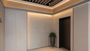 Un ascensor moderno con detalles metálicos, una planta en maceta y un techo con textura.