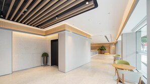 Un interior moderno con mostrador de recepción, zona de estar y ventanas amplias.