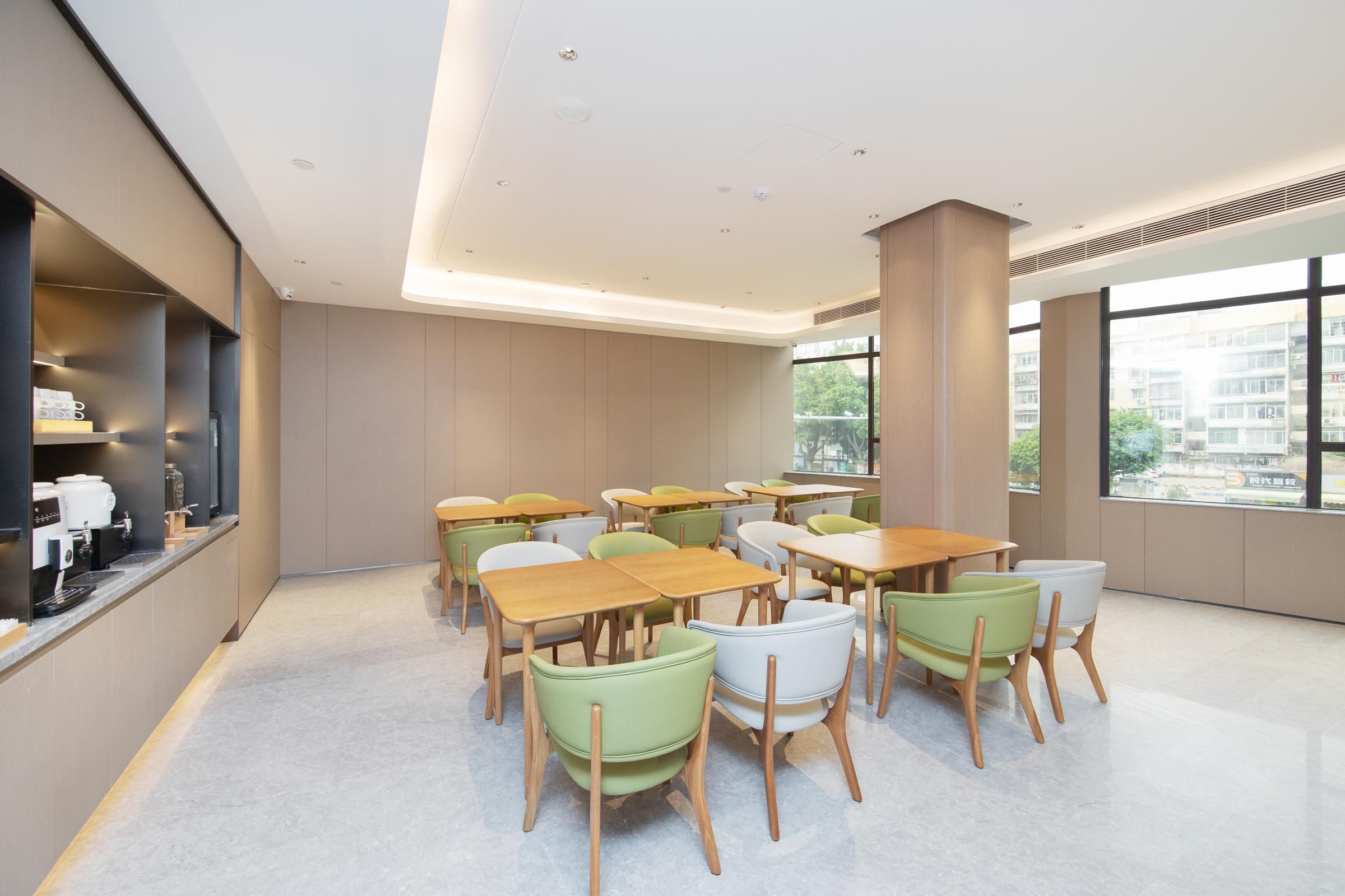 A modern dining area with tables and chairs, a coffee machine, and large windows.