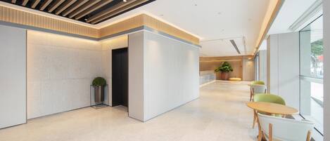 A modern interior with a reception desk, seating area, and large windows.