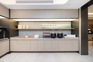 Une cuisine moderne dotée d’une cuisinière intégrée, d’un plan de travail avec des bocaux de rangement et d’une étagère pour les ustensiles de cuisine.
