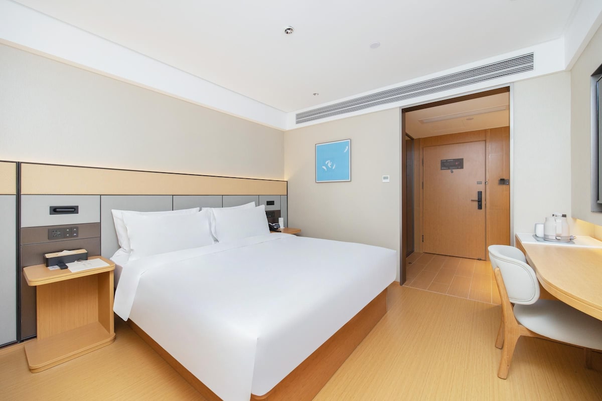 Une chambre d’hôtel comprenant un lit, une table de chevet, un bureau, une chaise et une porte.