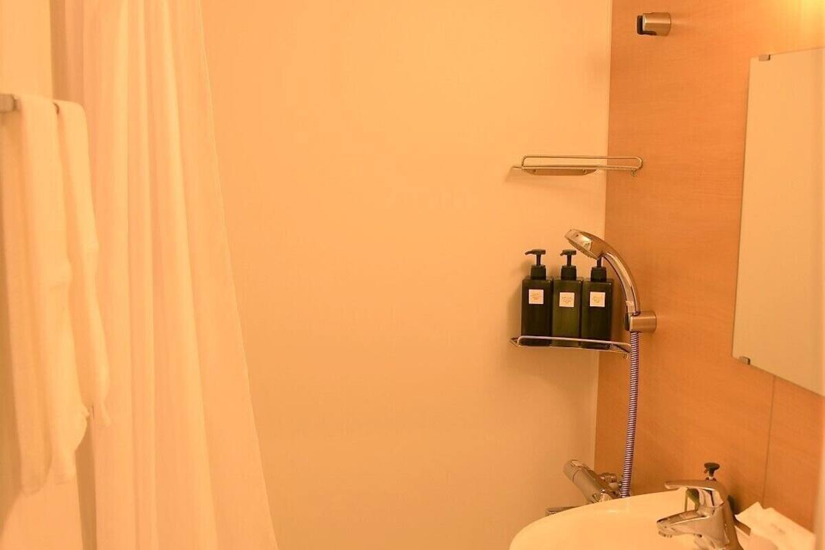 Un baño con bañera, lavabo e inodoro. Hay artículos de aseo en un estante.