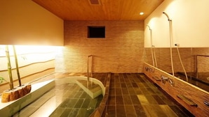 A spa area with a wooden ceiling, a stone wall, a glass tub, and a wooden bench. - Sekinoya (Kami)