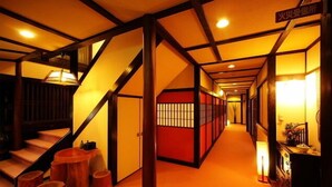 A hallway with a wooden staircase, a red partition, and a carpeted floor. - Sekinoya (Kami)