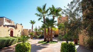 Un cortile con palme, un vialetto lastricato e architettura tradizionale.
