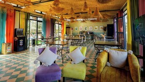 Un'ampia sala da pranzo con pavimento a scacchi, sedie colorate e un soffitto in paglia.