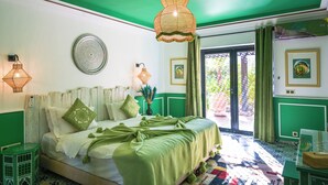 A bedroom with a green and white color scheme, a bed with a green blanket, two wall-mounted lamps, and a large window with curtains. - Maison Daouia (Marrakech)