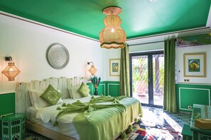 A bedroom with a green and white color scheme, a bed with a green blanket, two wall-mounted lamps, and a large window with curtains. - Maison Daouia (Marrakech)