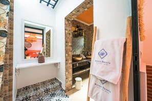 Un baño con baldosas estampadas, una ventana con vistas, un lavamanos y un perchero con toallas.