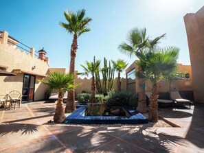 A courtyard with palm trees, a water feature, and a seating area. - Maison Daouia (Marrakech)