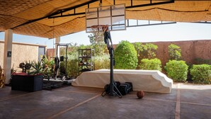 An outdoor basketball court with a hoop, exercise equipment, and a covered seating area. - Maison Daouia (Marrakech)