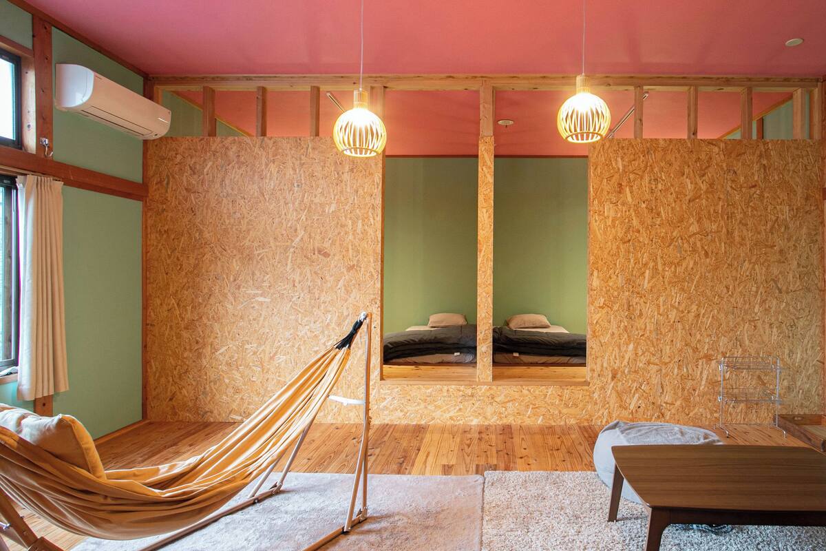 Ein Zimmer mit einer Hängematte, einem Holztisch und einem Bett mit Spiegel.