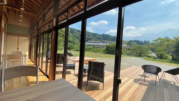 A room with large windows, wooden flooring, and a view of a traditional building and mountains. - MIZUKAMISO (Mizukami)